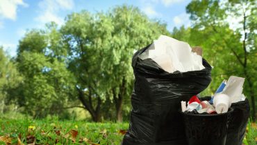 Full black wastebasket and plastic bags